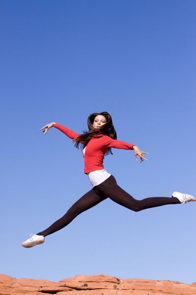زن جوان زیبا و پرشور ورزشی که پرش می کند