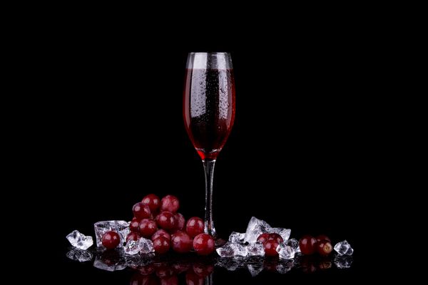 انگور قرمز با لیوان شامپاین بر روی زمینه سیاه