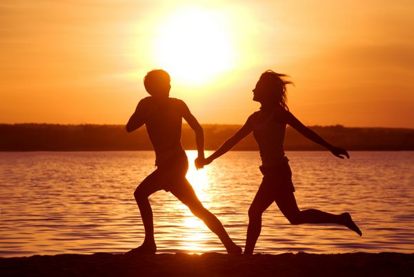 شبح های زوج خوشبختی که هنگام غروب آفتاب در ساحل دریا در حال شلیک هستند