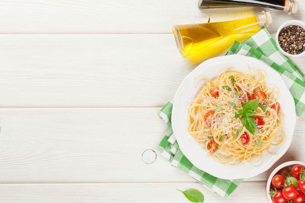 ماکارونی اسپاگتی با گوجه فرنگی و ریحان روی میز چوبی نمای بالا با فضای کپی