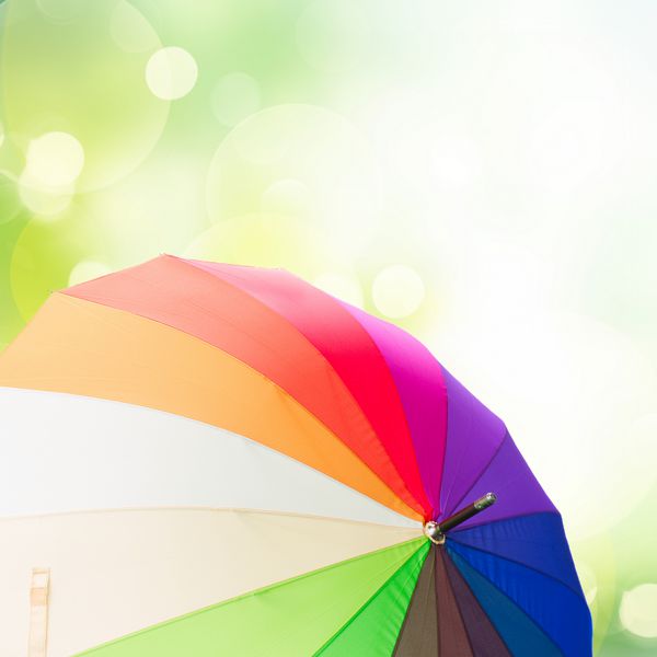 چترهای رنگین کمان را بر روی زمینه باغ سبز باز کنید