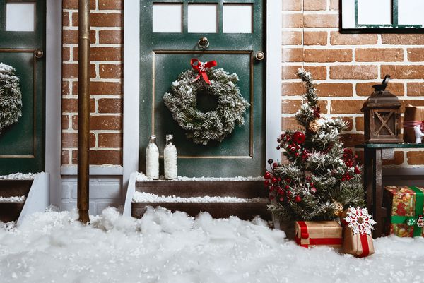 زمینه کریسمس با درب دیوار آجری نور خیابان برف و درخت کریسمس