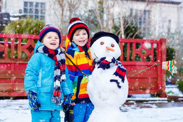 دو پسر خواهر و برادر کوچک که آدم برفی درست می کنند بچه ها و تفریح ​​با برف بیرون از منزل در روز سرد اوقات فراغت فعال در فضای باز با کودکان در فصل زمستان