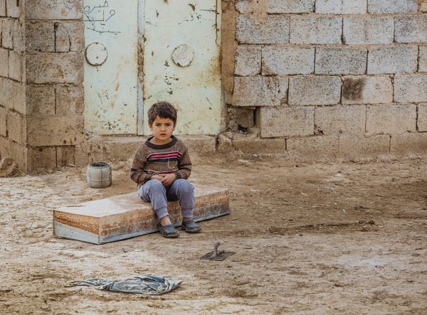 کرکوک عراق 29 دسامبر 2015 پسر کوچک یتیم در حومه عراق به حال خود رها شد والدین وی توسط تروریست های داعش کشته شدند و اکنون پیرزنی که در صحرای عراق از او مراقبت می کند