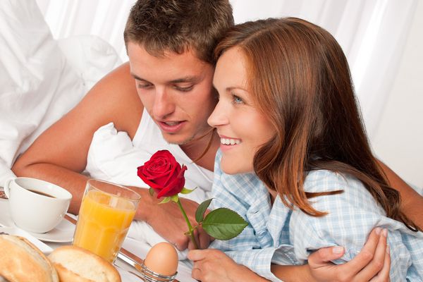زن و مرد مبارک با داشتن صبحانه هتل لوکس در رختخواب در کنار هم