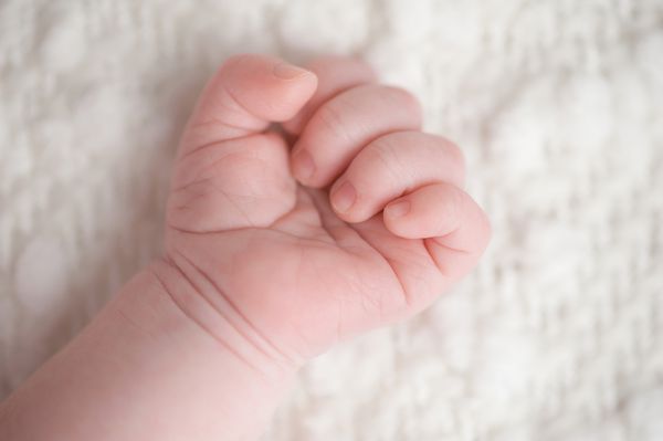 یک عکس نزدیک از یک پسر بچه سه هفته ای تازه متولد شده و دست x27؛