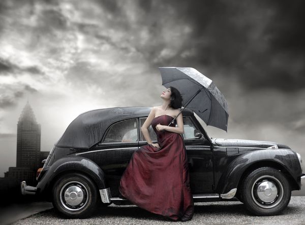 خانم با لباس بنفش و چتر در کنار ماشین لوکس پرنعمت