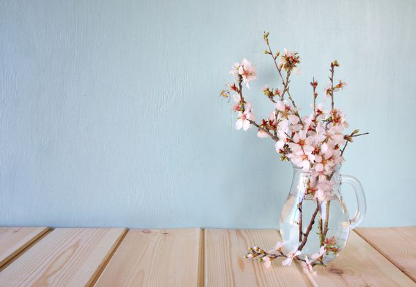 دسته گل های بهاری روی میز چوبی با زمینه نعنا تصویر فیلتر شده پرنعمت