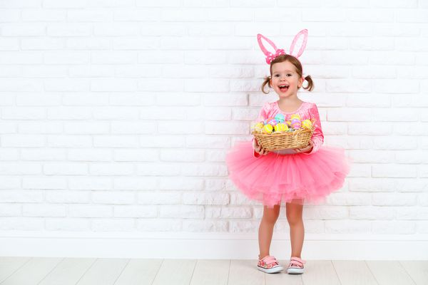 دختر کودک شاد در یک لباس خرگوش عید پاک عید پاک با گوش و یک سبد تخم مرغ