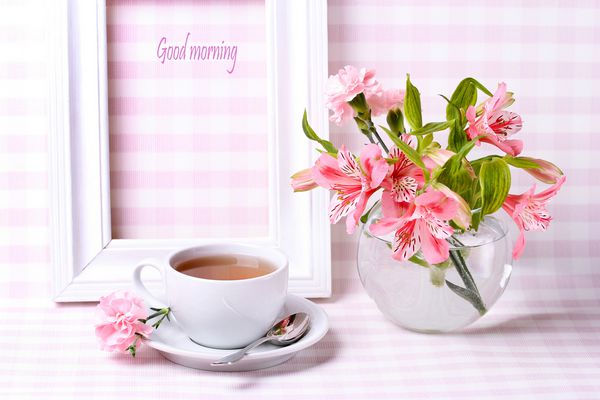 صبح بخیر فنجان چای قاب سفید و گلدان گل در یک زمینه زیبا
