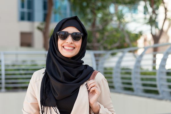 لبخند دختری در حجاب که با خوشحالی چشم هایش را در مارینای دبی می پوشاند