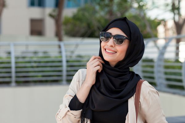 لبخند دختری در حجاب که با خوشحالی چشم هایش را در مارینای دبی می پوشاند