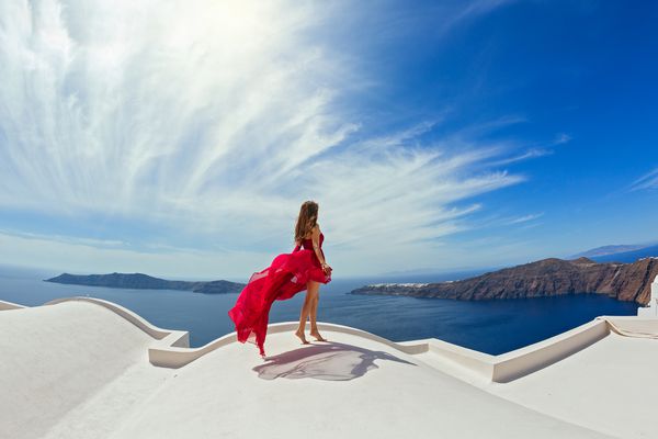 زن با لباس هوایی با لباس قرمز در پشت بام جزیره سانتورینی