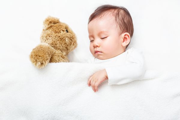 بهترین دوست من کودک با خواب خرس عروسکی خود در تختخواب خانواده جدید و مفهوم سالم کودک خوابیده است