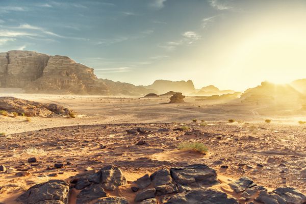 چشم انداز کویری وادی در اردن با غروب خورشید سنگ بوته و آسمان
