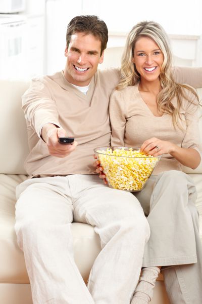 زن و شوهر جوان مبارک که در خانه تلویزیون تماشا می کنند