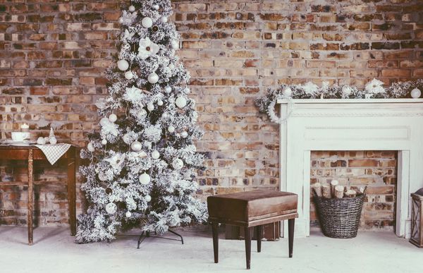دکوراسیون منزل زمستانی درخت کریسمس در فضای داخلی شیروانی در برابر دیوار آجری مبلمان قدیمی پرنعمت