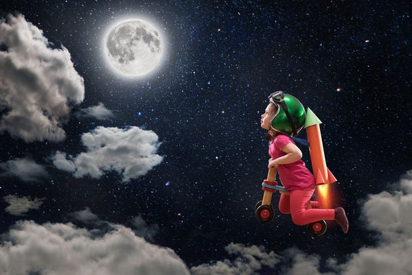 یک رویا در کودکی دختر بچه ناز که با دوچرخه خود به ماه پرواز می کند کلاه ایمنی می پوشد و یک موشک مقوایی ساخته شده بر پشت او قلاب کرده است