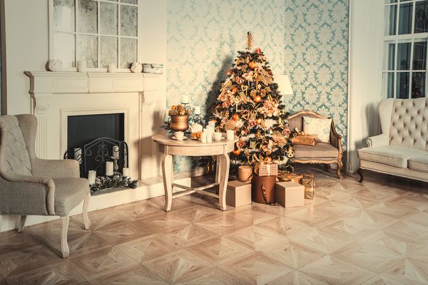 داخلی لوکس اتاق نشیمن با تزیین درخت کریسمس و هدایا در کف چوبی