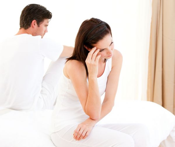 زن و شوهر ناراضی با یک استدلال که روی تخت خود نشسته اند