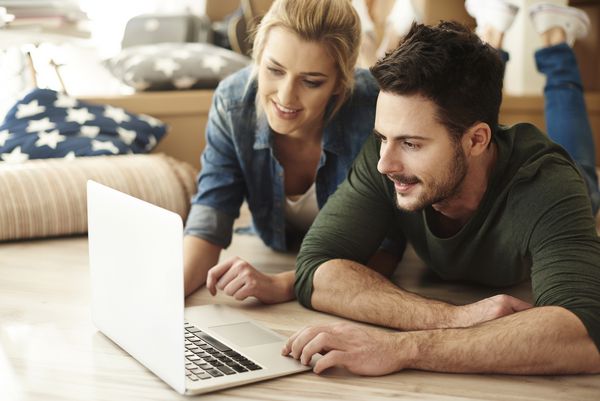 زن و شوهر جوان در آپارتمان جدید با استفاده از لپ تاپ