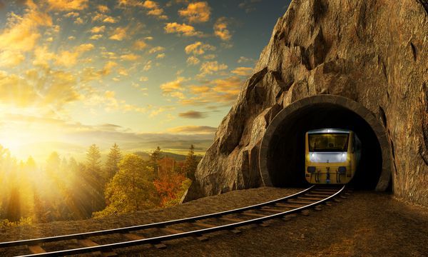 راه آهن کوهستانی با قطار در تونل منظره غروب خورشید در زیر صخره بزرگ