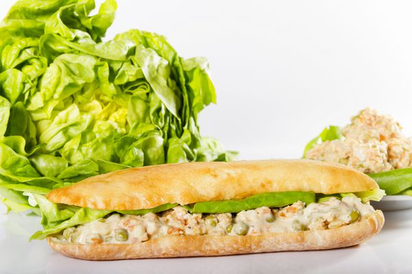 ساندویچ نان سیاباتا با روسی سالاد اولیویه و کاهو در کنار مواد