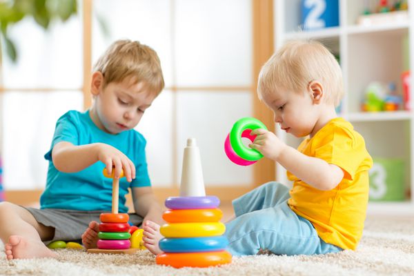 بچه ها با هم کودک و نوزاد نوپا با بلوک بازی می کنند اسباب بازی های آموزشی برای کودک پیش دبستانی و کودکستان پسران کوچک اسباب بازی های هرمی را در خانه یا مهد کودک می سازند
