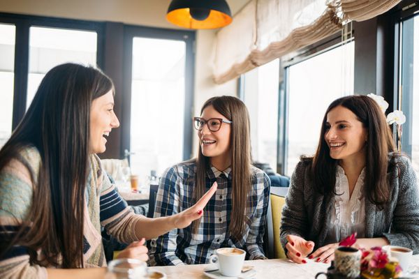 گروه جوانی از دوستان زن که در کافی شاپ نشسته اند و از مکالمه قهوه لذت می برند مفهوم قهوه با هم بودن جلسه دوستانه