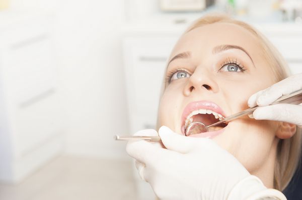 نزدیک دندانهای دندانپزشکی که روی دندانهای زنانه جذاب کار می کنند