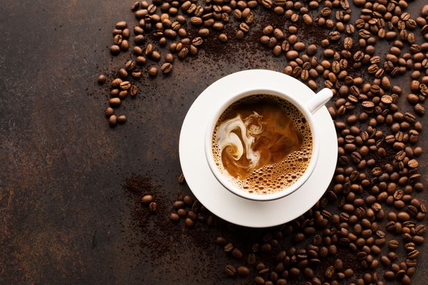 فنجان قهوه اسپرسو و شیر یا خامه را بر روی پس زمینه یکپارچهسازی با سیستمعامل تیره با لوبیا ریخت نمای بالا با فضای کپی برای متن مفهوم عشق قهوه صبحانه