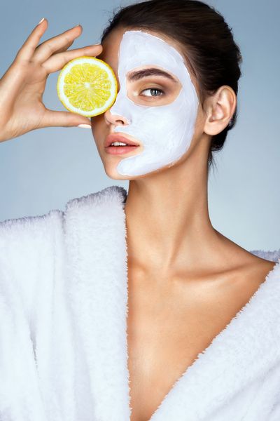 زنی که جلوی صورت خود یک تکه لیمو نگه داشته است عکس زن با ماسک مرطوب کننده صورت زیبایی و آمپر؛ مفهوم مراقبت از پوست