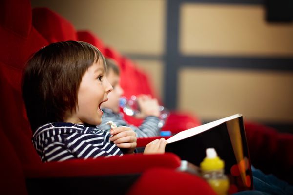 دو کودک پیش دبستانی برادرهای دوقلوی در حال تماشای فیلم در سینما خوردن پاپ کورن هستند