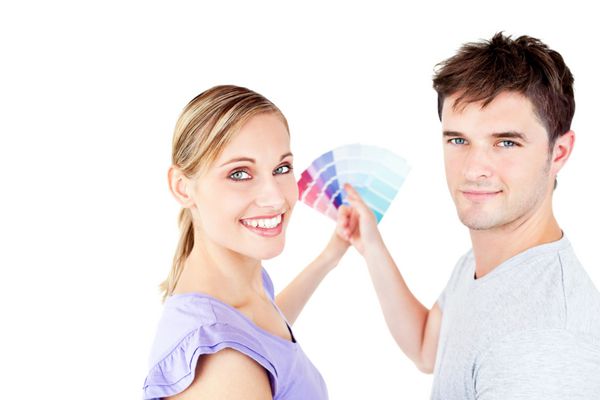 لبخند زن و شوهر جوانی که رنگ اتاق را در خانه جدیدشان انتخاب می کند