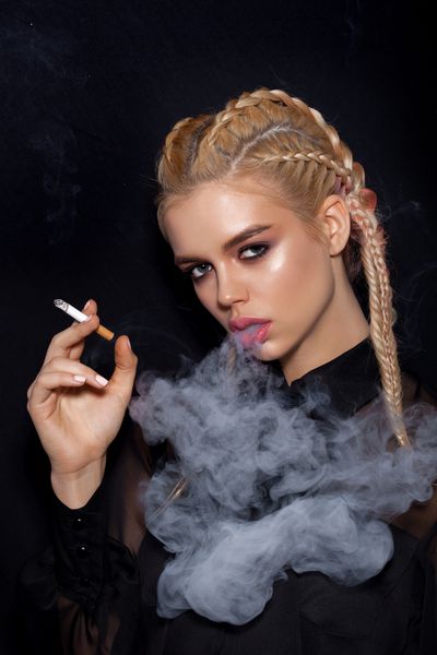 زن زیبا با سیگار کشیدن لباس سیاه دختری با رنگدانه های روی زمینه تاریک جدا نشده