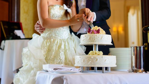 عروس و داماد در حال برش کیک عروسی هستند
