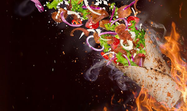 نزدیک ساندویچ کباب با مواد پرنده با پس زمینه شعله های آتش