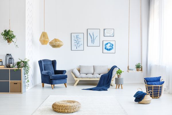 اتاق نشیمن سفید با مبل چوبی صندلی آبی لامپ پوستر