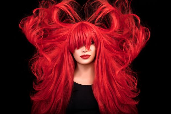 دختر مدل زیبایی با موهای قرمز بلند قرمز و موهای بلند و پوشاننده چشم با رژ لب قرمز و آرایش روشن مفهوم زیبایی رنگ مو پرواز موهای بلند پرتره جدا شده در پس زمینه سیاه