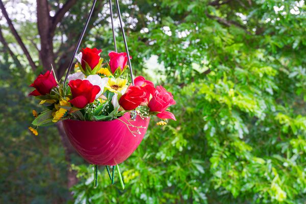 گل های مصنوعی رنگارنگ در گلدان های آویز در گلدان تزئین شده در باغ
