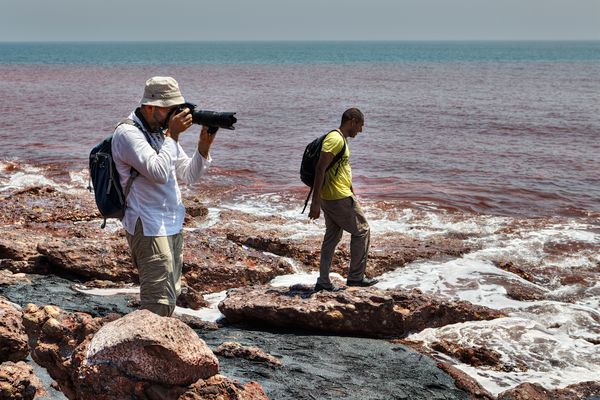 جزیره هرمز استان هرمزگان ایران 17 آوریل 2017 دو گردشگر در ساحل جزیره آتشفشانی قدم می زنند و از آنها عکس می گیرند