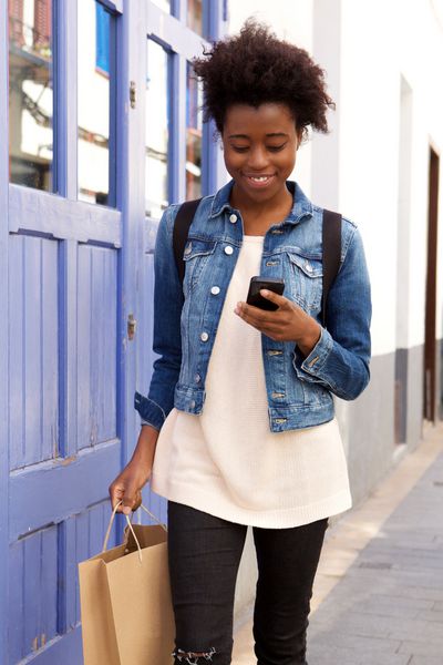 پرتره زن آمریکایی تبار با کیسه خرید با استفاده از تلفن همراه