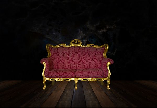 صندلی لوکس کلاسیک چوبی حک شده طلایی در یک اتاق تاریک
