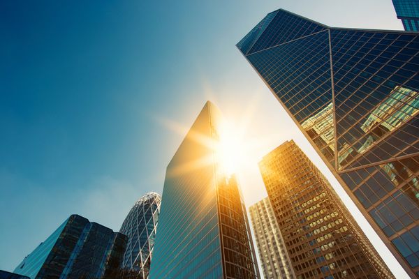 نمای شیشه ای آسمان خراش در یک روز آفتابی روشن و پرتوهای آفتاب در آسمان آبی ساختمانهای مدرن در منطقه تجاری La Defense در پاریس اقتصاد امور مالی مفهوم فعالیت تجاری نمای پایین