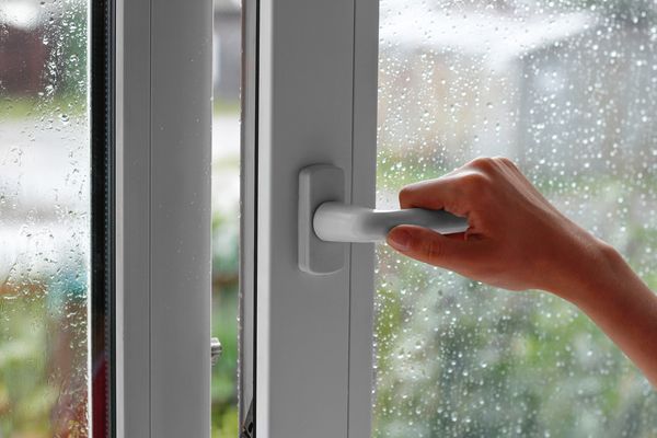 یک دست زن یک پنجره با قطره آب باز می کند پنجره را می بندد در هوای بارانی نزدیک