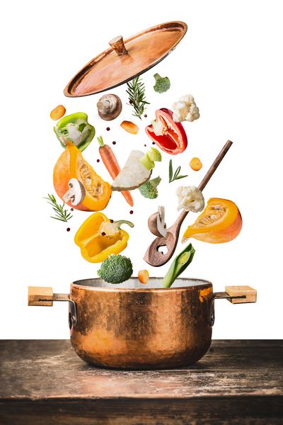 خوردن و آشپزی گیاهخواران سالم با انواع مواد اولیه سبزیجات خرد شده قابلمه آشپزی و قاشق در میز میز چوبی جدا شده در زمینه سفید نمای جلوی مفهوم مواد غذایی تمیز
