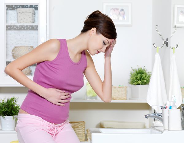 خانم باردار با درد شدید معده و حالت تهوع که در حمام نشسته است