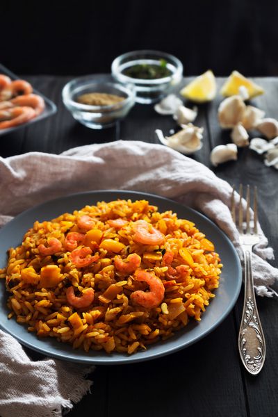 عکس عمودی برنج سرخ شده با میگو لیمو و سبزیجات روی صفحه خاکستری و کتان