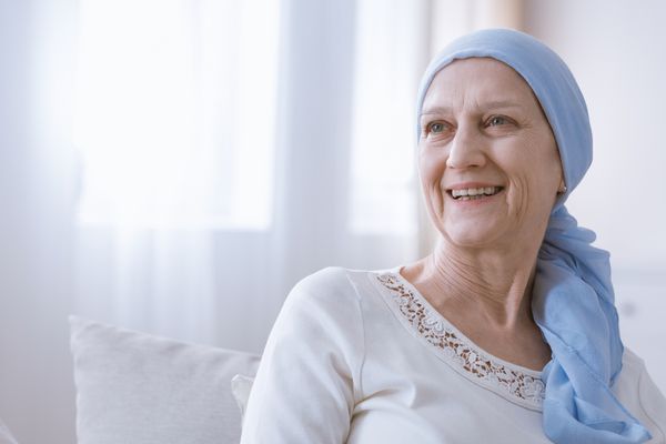 زن مبارک مبتلا به سرطان در روسری آبی که با امید لبخند می زند