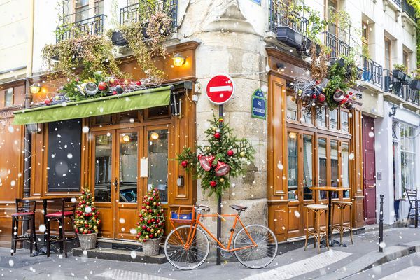 دوچرخه در کافه های معمولی پاریسی که برای تعطیلات کریسمس در پاریس فرانسه تزئین شده اند پارک شده است
